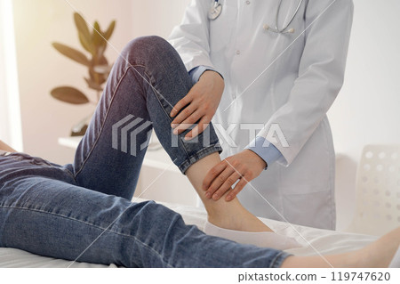 Doctor and patient are at the medical inspection in clinic. Orthopedic examines the knee of a young woman. Medicine concept Doctor and patient are at the medical inspection in clinic. Orthopedic examines the knee of a young woman. Medicine concept 119747620