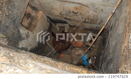 Old concrete cellar filled with accumulated garbage and debris in a neglected underground space 119747829