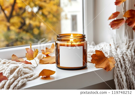 Amber glass candle jar with blank white label mockup, burning candle in Christmas holiday decorated home interior, seasonal cozy decor 119748252
