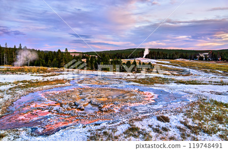 Sunset Over Hot Springs at Upper Geyser Basin with Old Faithful Erupting in the Background, Yellowstone National Park, United States 119748491