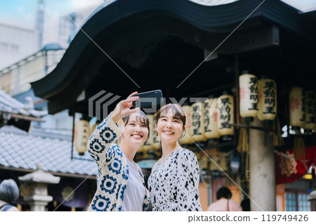 A woman taking a selfie with friends while sightseeing in Osaka A woman taking a selfie with friends while sightseeing in Osaka 119749426