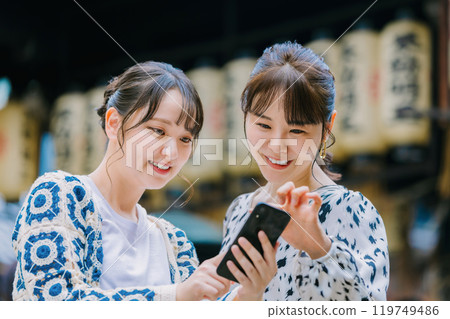 一位女士在大阪觀光時與朋友一起看智慧型手機 119749486
