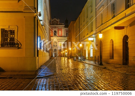 Narrow cobblestone street with illuminated facades at night, Poznan, Poland 119750006