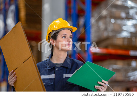 Female warehouse worker holding paper product and clipboard checking inspecting quality cardboard corrugated carton in storage. Large industry in paper product line manufacturing. 119750590