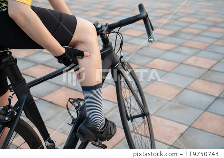 Cropped shot of cyclist having calf strain from cycling. Tight calves can be caused from overusing the muscles and from not warming up before you hop on your bike. 119750743