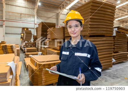portrait of woman paper warehouse worker holding clipboard looking at camera. Employees warehouse checking quality cardboard in storage. Large industry in paper product line manufacturing. 119750903