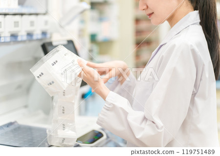 A pharmacist who uses an automatic packaging machine at a pharmacy or drug store to prepare powdered medicine, dispensing, and prescriptions 119751489
