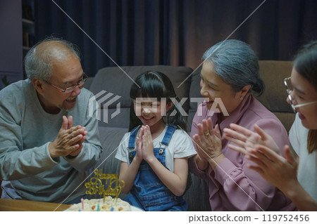 Happy Asian family grandparents and mother celebrating enjoy singing birthday song party with cake of granddaughter blowing candle at home in night time, Birthday surprise concept Happy Asian family grandparents and mother celebrating enjoy singing birthday song party with cake of granddaughter blowing candle at home in night time, Birthday surprise concept 119752456