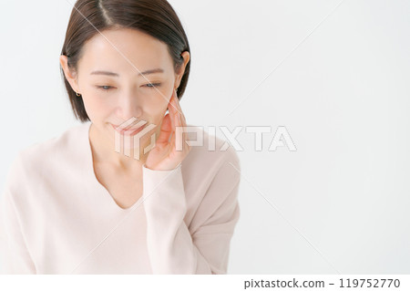 A woman in her 30s smiling with her hand on her cheek A woman in her 30s smiling with her hand on her cheek 119752770