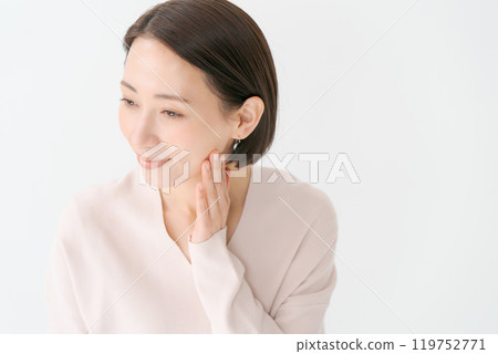 A woman in her 30s smiling with her hand on her cheek 119752771