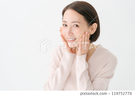 一名 30 多歲的女性，手放在臉頰上微笑 119752778