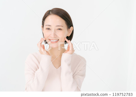 A woman in her 30s smiling with her hand on her cheek A woman in her 30s smiling with her hand on her cheek 119752783