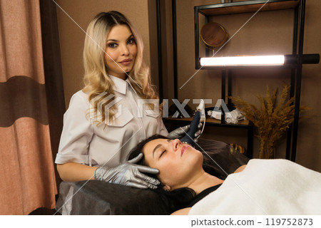 Cosmetologist conducting phonophoresis ultrasound therapy on woman's face 119752873