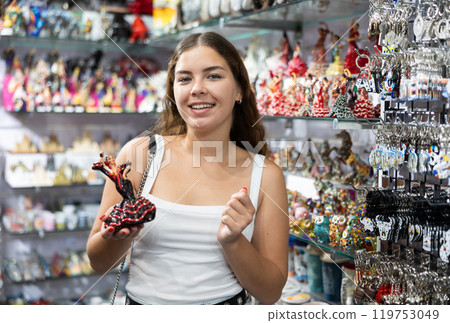 Interested young woman viewing Spanish dancer statuettes in souvenir store in Barcelona Interested young woman viewing Spanish dancer statuettes in souvenir store in Barcelona 119753049