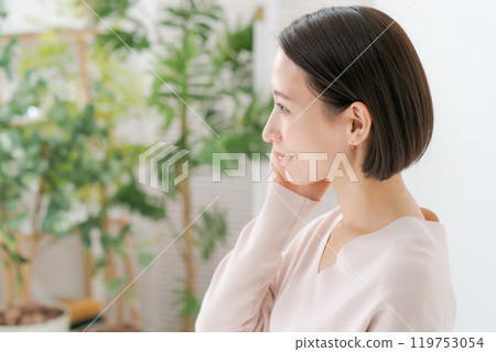 A woman in her 30s smiling with her hand on her cheek 119753054