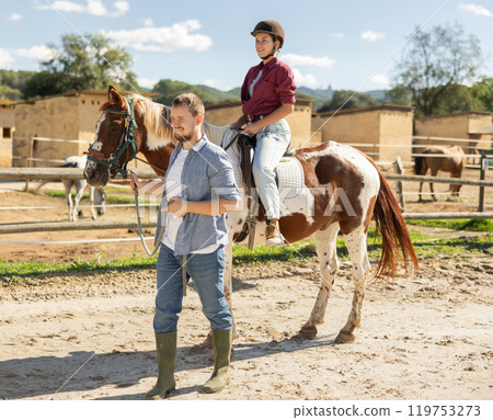 Young man leading horse with woman riding Young man leading horse with woman riding 119753273