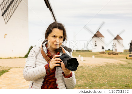 Tourist with camera in front of the windmills of the Mota del cuervo. Spain 119753332
