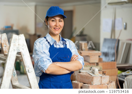 Portrait of a positive woman builder standing near a stepladder 119753416