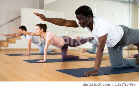 Man doing bird dog exercise during group fitness training Man doing bird dog exercise during group fitness training 119753486