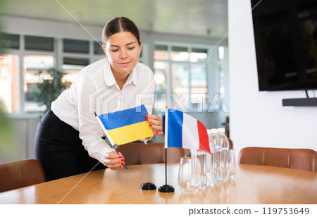 Young woman puts flags of Ukraine and France on table in office Young woman puts flags of Ukraine and France on table in office 119753649