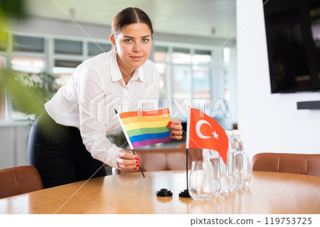 Positive young woman putting little LGBT flag on table next to the flag of Turkey 119753725