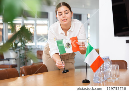 Young woman puts flags of Mexico and Italy on table Young woman puts flags of Mexico and Italy on table 119753736