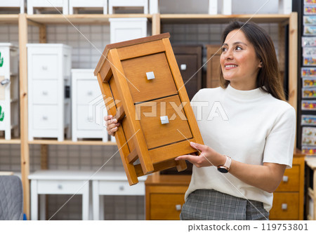 Woman choosing small wooden cabinet at shop Woman choosing small wooden cabinet at shop 119753801