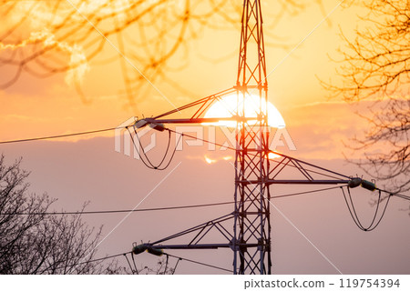A stunning sunset view with the silhouette of power lines and a transmission tower behind it 119754394