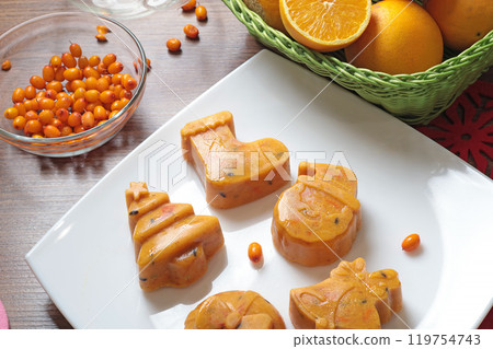 Frozen sea buckthorn and orange tea in Christmas molds on white plate in kitchen. Healthy eating and seasons.  119754743