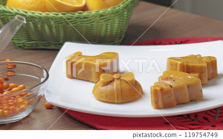 Frozen sea buckthorn and orange tea in Christmas molds on white plate in kitchen. Healthy eating and seasons.  119754749