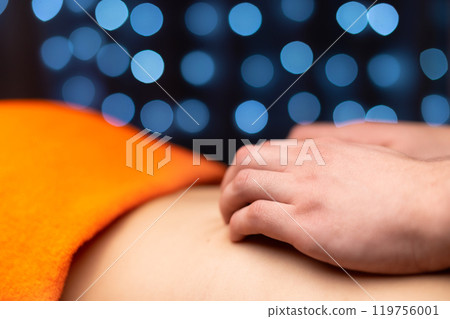 Close-up of a man's hands with a delabt massager massaging the trapezius muscle of a young woman. Low key. massage and physical health concept Close-up of a man's hands with a delabt massager massaging the trapezius muscle of a young woman. Low key. massage and physical health concept 119756001