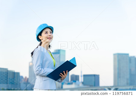 A female designer and architect wearing a helmet and looking at the city 119756871