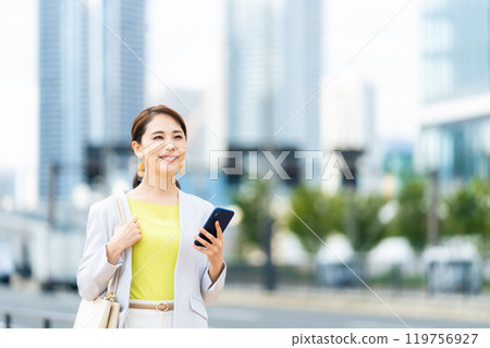 A woman holding a smartphone on a street corner Mobile communication Taxi dispatch app 119756927