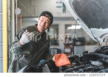 Middle-aged Asian man, mechanic, auto mechanic working at a repair shop Middle-aged Asian man, mechanic, auto mechanic working at a repair shop 119757177