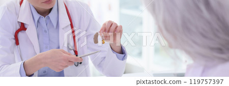 Woman doctor gives hearing aid to client at workplace Woman doctor gives hearing aid to client at workplace 119757397