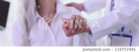 Female doctor helps sick mature woman stand up in office Female doctor helps sick mature woman stand up in office 119757445