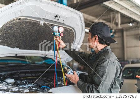 Male auto mechanic using a manifold gauge Male auto mechanic using a manifold gauge 119757768