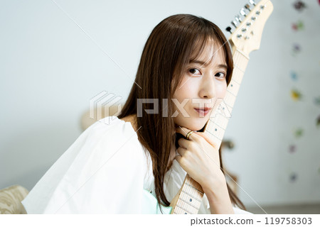 Long-haired young woman with an electric guitar Long-haired young woman with an electric guitar 119758303