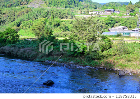 The Tone River in the early morning with the morning sun shining on it. Near Komatsu Power Plant. Scenery of houses along the river. Minakami Town. 119758313