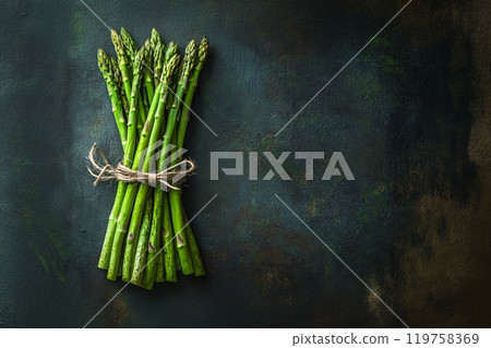 A bunch of asparagus, tied with twine, rests against a rustic background 119758369
