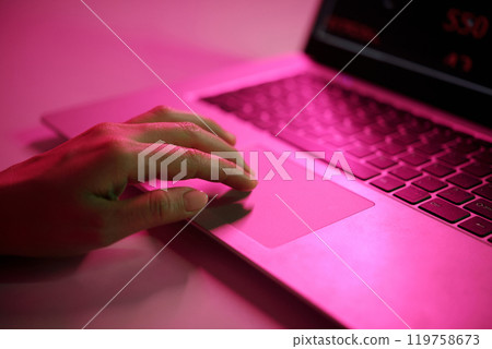 Hand Typing on Laptop with Pink Light Reflection 119758673