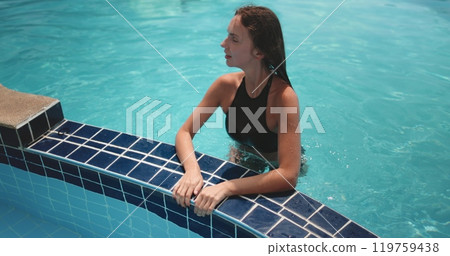 Woman relax on swimming pool edge in crystal water, Koh Phangan Island resort, Thailand. Girl in bikini enjoy and have fun in hotel. Lifestyle holiday concept during summer vacation. Slow 119759438