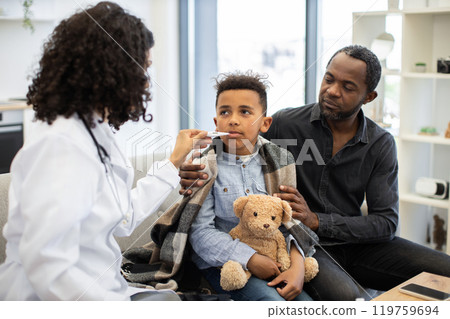 African female doctor checks temperature of young boy at home African female doctor checks temperature of young boy at home 119759694