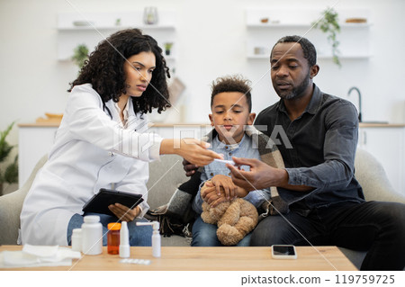 African female doctor assisting father and son with thermometer at home African female doctor assisting father and son with thermometer at home 119759725