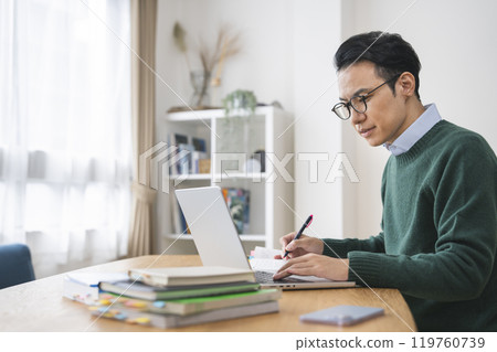 A man in his late 30s working at a desk 119760739