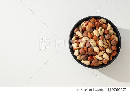 Assorted nuts in a black bowl on a white background Assorted nuts in a black bowl on a white background 119760971