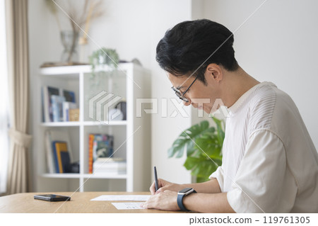 一名 30 多歲的男子，身材矮小，正在填寫文件 119761305