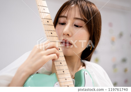 拿著電吉他的長髮年輕女子 119761740