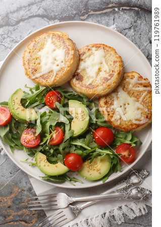 Eggy cheese crumpets with vegetables salad closeup on the plate. Vertical top view Eggy cheese crumpets with vegetables salad closeup on the plate. Vertical top view 119761989