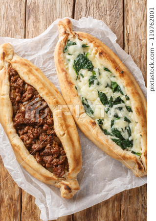 Pide is a Turkish pizza-like dish made from a boat-shaped flatbread with filling close-up. Vertical top view 119762001